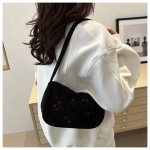 Detailed texture of black corduroy shoulder bag with sweet red cherry print pattern
