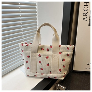 Close-up of strawberry embroidery on corduroy mini tote with a front outer pocket