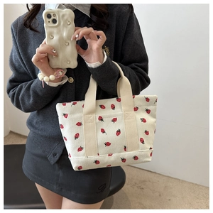 Detail of strawberry print corduroy tote bag with textured beige ribbon handles