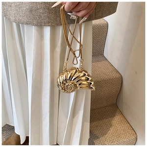 Detail of a metallic gold shell-shaped clutch with a delicate gold snake chain