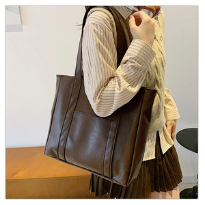 Detailed side view of large brown faux leather tote bag with vertical stitching