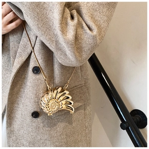 Macro detail of golden nautilus shell-shaped mini chain bag with metallic spiral texture