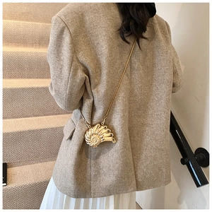 Detailed view of a gold shell-shaped mini chain bag with metallic spiral texture