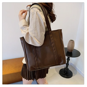 Detail view of large dark brown tote bag with vertical stitching and flat outer pocket