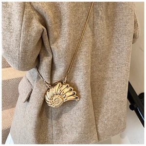 Detail of gold seashell-shaped mini chain bag worn with a brown herringbone blazer