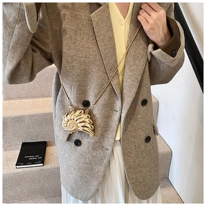 Detail of creative shell-shaped gold metal crossbody bag with chain on a model