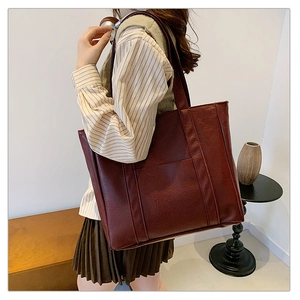 Close-up of a large dark red leather tote bag with vintage texture and long shoulder strap