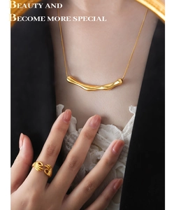 Gros plan du pendentif géométrique doré et de la bague câlin sur une tenue élégante
