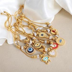 Pulsera dorada ojo turco con colgantes hamsa y circonitas sobre satén blanco