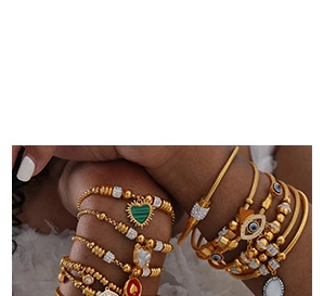 Détail de bracelets bohèmes en perles dorées avec pendentifs cœur et breloques œil
