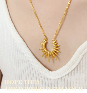 Gros plan d'un collier doré avec pendentif rayon de soleil porté sur le décolleté