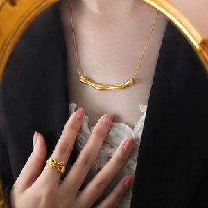 Collier doré irrégulier et bague en forme de main OK portés par un mannequin