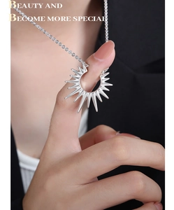 Détail d'un collier avec pendentif étoile argenté tenu devant un blazer noir