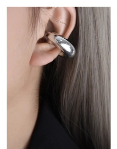 Vue macro d'une boucle d'oreille épaisse en argent poli au design géométrique minimaliste