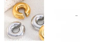 Gros plan de boucles d'oreilles épaisses en C dorées et argentées au style minimaliste