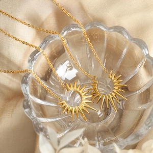 Collier en acier titane doré avec pendentif étoile solaire sur un plat en verre