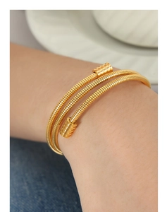 Gros plan du bracelet triple spirale doré à texture serpent au poignet d'une femme