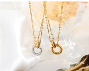 Detalle de collares minimalistas de acero de titanio con doble aro sobre seda blanca