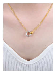 Detalle de los anillos entrelazados de oro y plata en una cadena de collar fina