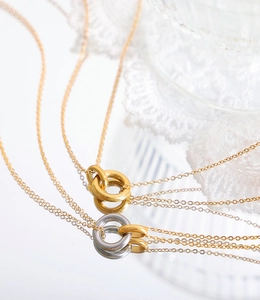 Detalle de colgantes de doble anillo entrelazado en oro y plata en cadenas finas