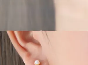 Close-up of a French style round pearl earring with gold trim on a model's ear