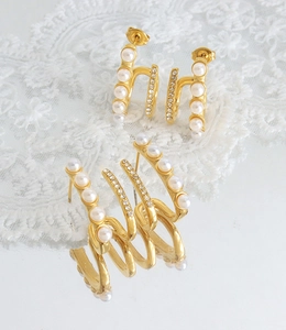 Detail of French style gold-plated steel earrings with white pearls and sparkling rhinestones