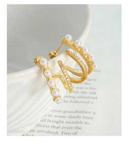 Detail of gold-plated wave-shaped earrings with faux pearls and micro-pave crystals