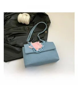 Detail showing light blue denim bag with pink frayed star patch and plastic chain