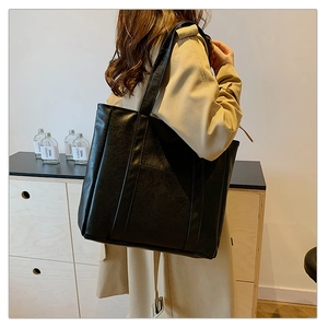 Detail of a large black leather tote bag with vertical stitching for daily commute