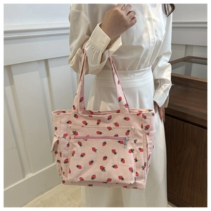 Detail of pink corduroy tote bag featuring strawberry patterns and functional front pocket