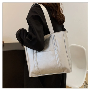 Side view of silver tote bag with crackle texture worn by model in minimalist setting