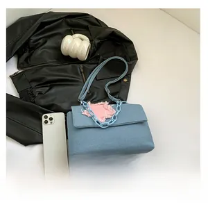 Detailed view of blue denim crossbody bag featuring a pink frayed star patch and thick chain