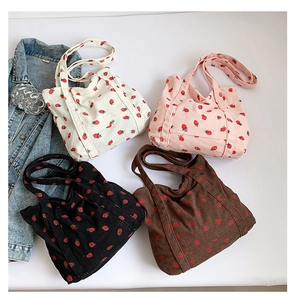 Detailed flat lay of corduroy tote bags in four colors with strawberry patterns