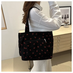 Detail of strawberry print on black corduroy tote bag showing side pockets and texture