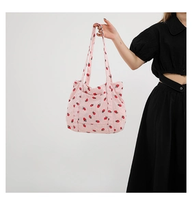 Dettaglio della borsa tote in velluto a coste rosa con stampe di fragole e doppi manici