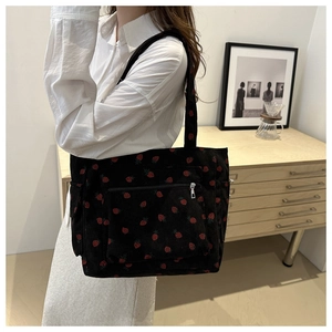 Detail of black corduroy tote bag with strawberry print and silver metal zipper pocket