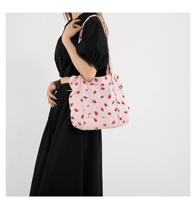 Detailed texture of pink corduroy tote bag with strawberry print worn by a model