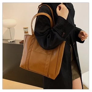 Brown leather tote bag featuring a minimalist rectangular silhouette and front vertical seam