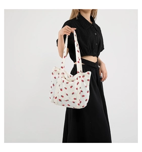 Detail of large capacity corduroy tote bag featuring red strawberry patterns on cream fabric
