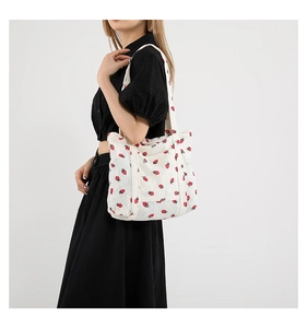 Detailed side view of a white corduroy tote bag featuring a red strawberry print pattern