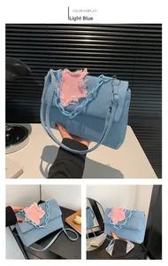 Detail of light blue denim shoulder bag with pink frayed star patch and blue chain strap