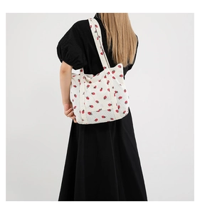 Detail of white corduroy tote bag featuring red strawberry patterns and double straps