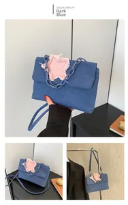 Detail of dark blue denim bag featuring a pink star patch and blue acrylic chain