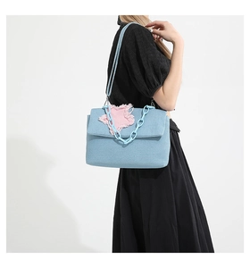 Close-up of light blue denim shoulder bag with pink plush star patch and plastic chain