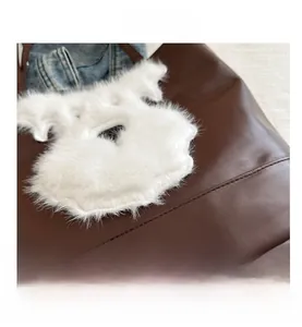 Détail du sac cabas en cuir marron foncé avec écusson chiot en peluche et couture fine