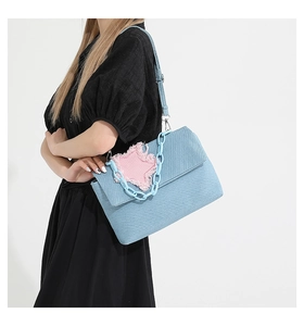 Detail of denim crossbody bag featuring pink star patch and blue plastic chain strap