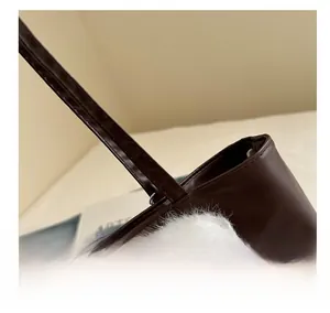 Vue détaillée du sac en cuir marron avec coutures précises et charme en peluche blanche