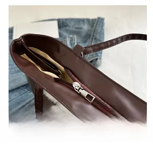 Détail de la fermeture éclair en métal et de la doublure en tissu beige sur le sac marron
