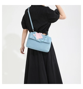 Detail of light blue denim bag with a pink star patch and plastic chain shoulder strap