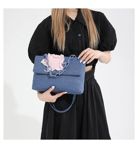 Close-up of blue denim handbag with pink frayed star patch and plastic chain strap